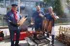 Drei Männer bereiten am Grill Flammlachs und Fischbrötchen beim Fischerfest in Bad Lippspringe zu.