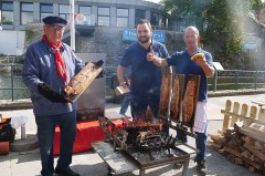 Drei Männer bereiten am Grill Flammlachs und Fischbrötchen beim Fischerfest in Bad Lippspringe zu.