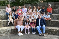 Teilnehmende Kinder und vier Erwachsene von FIT in Deutsch an der Josefschule Büren sitzen für ein Gruppenfoto auf Steinstufen.