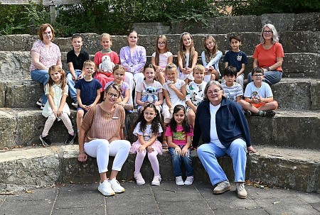 Teilnehmende Kinder und vier Erwachsene von FIT in Deutsch an der Josefschule Büren sitzen für ein Gruppenfoto auf Steinstufen.