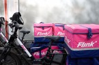 Flink-Lieferfahrräder mit pink-blauen Transportboxen stehen nebeneinander.