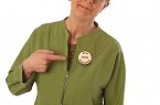 Frau in grüner Jacke zeigt auf einen Button mit der Aufschrift „Bitte nicht ansprechen“.