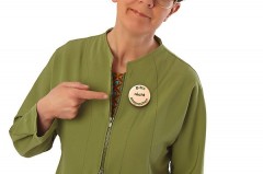 Frau in grüner Jacke zeigt auf einen Button mit der Aufschrift „Bitte nicht ansprechen“.