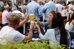 Besucherinnen und Besucher stoßen beim Gourmetmarkt auf dem Kolbeplatz mit Bier und Wein an.