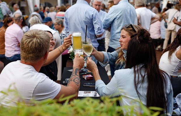 Besucherinnen und Besucher stoßen beim Gourmetmarkt auf dem Kolbeplatz mit Bier und Wein an.