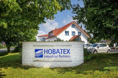 Firmengebäude von HOBATEX in Brakel hinter einem großen HOBATEX-Industrial-Partners-Schild.