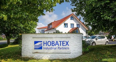Firmengebäude von HOBATEX in Brakel hinter einem großen HOBATEX-Industrial-Partners-Schild.