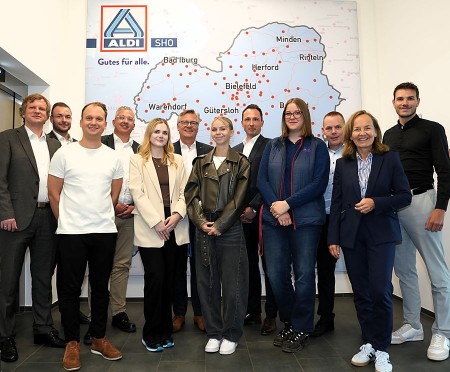 Gruppe aus zwölf Personen vor einer ALDI-Karte mit Standorten in Ostwestfalen