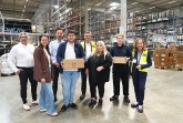 Gruppenfoto der IHK-Ausbildungstour bei SK Pharma Logistics in einer Lagerhalle in Bielefeld; zwei junge Beschäftigte halten Pakete.