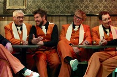 Die sechs Musiker der Jazz Connection sitzen in orangefarbenen Anzügen gemeinsam in einem Clubraum.