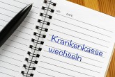 Schwarzer Kugelschreiber auf einem offenen Notizbuch mit der Aufschrift „Krankenkasse wechseln“.