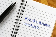 Schwarzer Kugelschreiber auf einem offenen Notizbuch mit der Aufschrift „Krankenkasse wechseln“.