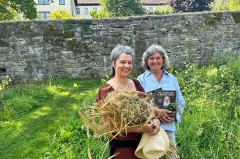 Zwei Frauen im Abteigarten Marienmünster, eine mit einem Krautbund und die andere mit einem Buch.