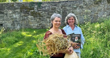 Zwei Frauen im Abteigarten Marienmünster, eine mit einem Krautbund und die andere mit einem Buch.