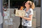 Britta Köster steht vor dem Bürener Pop-up-Store und hält ein graviertes Holzschild zur Geburt in den Händen.