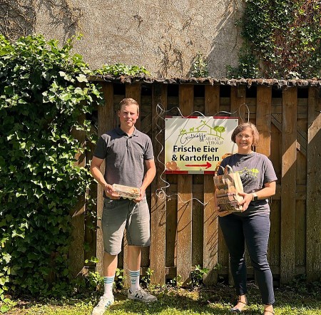 Drei Personen mit bedruckten Bierdeckeln der Bürgerbrauzunft Nieheim vor einem Holzfass.