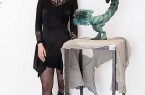 Linda Marwan steht neben einer grün-schwarzen hybriden Skulptur auf einem Metalltisch.
