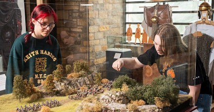 Zwei junge Museumsbesucher betrachten eine historische Miniaturlandschaft im LWL-Museum in der Kaiserpfalz.