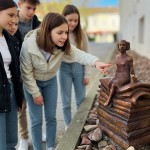 Fünf Kinder und Jugendliche betrachten eine kleine Märchenfigur, die auf einem Stapel Bücher sitzt.