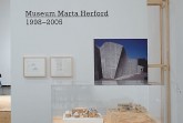 Ausstellungsbereich im Marta Herford mit Holzrahmenkonstruktion, Vitrine und Architekturaufnahme des Museums.