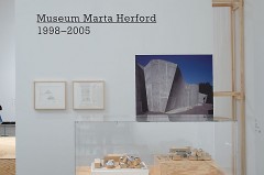 Ausstellungsbereich im Marta Herford mit Holzrahmenkonstruktion, Vitrine und Architekturaufnahme des Museums.