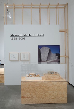 Ausstellungsbereich im Marta Herford mit Holzrahmenkonstruktion, Vitrine und Architekturaufnahme des Museums.