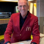Mann in rotem McDonald's-Sakko mit einer McCafé-Tasse im modernisierten Restaurant.