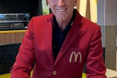 Mann in rotem McDonald's-Sakko mit einer McCafé-Tasse im modernisierten Restaurant.