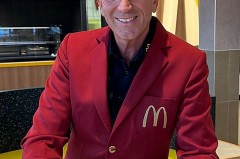 Mann in rotem McDonald's-Sakko mit einer McCafé-Tasse im modernisierten Restaurant.