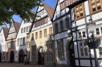 Historische Fachwerkhäuser des Mindener Museums an einer gepflasterten Straße unter blauem Himmel.