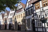Historische Fachwerkhäuser des Mindener Museums an einer gepflasterten Straße unter blauem Himmel.