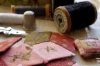 Nähutensilien mit Garnrollen, Fingerhut, Schere und handgenähten Stoffstücken in Rot- und Rosatönen