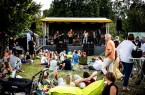 Band auf der Bühne beim Picknick-Konzert an der Krullsbachaue vor sitzendem Publikum © Matheus Fernandes