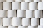 Gestapelte Rollen weißen Toilettenpapiers mit geprägten Mustern.