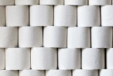 Gestapelte Rollen weißen Toilettenpapiers mit geprägten Mustern.