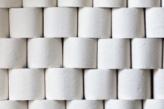 Gestapelte Rollen weißen Toilettenpapiers mit geprägten Mustern.