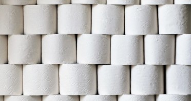 Gestapelte Rollen weißen Toilettenpapiers mit geprägten Mustern.