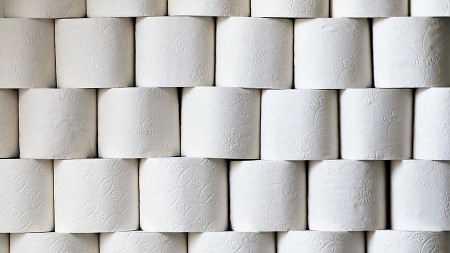 Gestapelte Rollen weißen Toilettenpapiers mit geprägten Mustern.