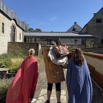 Drei Personen in römisch anmutenden Gewändern stehen im Innenhof des LWL-Museums in der Kaiserpfalz in Paderborn.