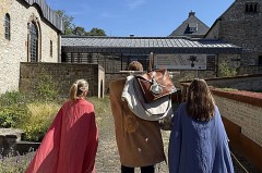 Drei Personen in römisch anmutenden Gewändern stehen im Innenhof des LWL-Museums in der Kaiserpfalz in Paderborn.