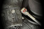 Schwarzer Zylinder, gemusterte schwarze Kleidung und ein Gehstock mit Totenkopfgriff.