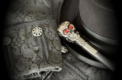 Schwarzer Zylinder, gemusterte schwarze Kleidung und ein Gehstock mit Totenkopfgriff.