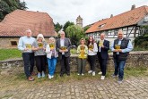 Acht Personen präsentieren Broschüren zum Tag des offenen Denkmals vor historischen Gebäuden in Lippe.