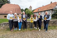 Acht Personen präsentieren Broschüren zum Tag des offenen Denkmals vor historischen Gebäuden in Lippe.