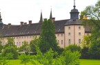 Historische Kloster- und Schlossanlage Corvey hinter einer grünen Parkanlage mit Bäumen.