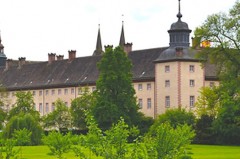 Historische Kloster- und Schlossanlage Corvey hinter einer grünen Parkanlage mit Bäumen.