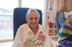 Ältere Patientin sitzt lächelnd im Wohnzimmer-Projekt im Klinikum Gütersloh.