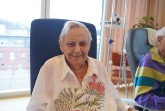 Ältere Patientin sitzt lächelnd im Wohnzimmer-Projekt im Klinikum Gütersloh.