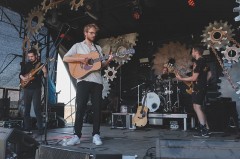 Vier Musiker der Band ETAGE3 spielen mit Gitarren, Bass und Schlagzeug auf einer Bühne.