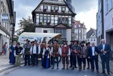Alt-Text: Historische Schützen in traditionellen Uniformen und Gewändern mit einem Planwagen vor dem Historischen Rathaus in Höxter.